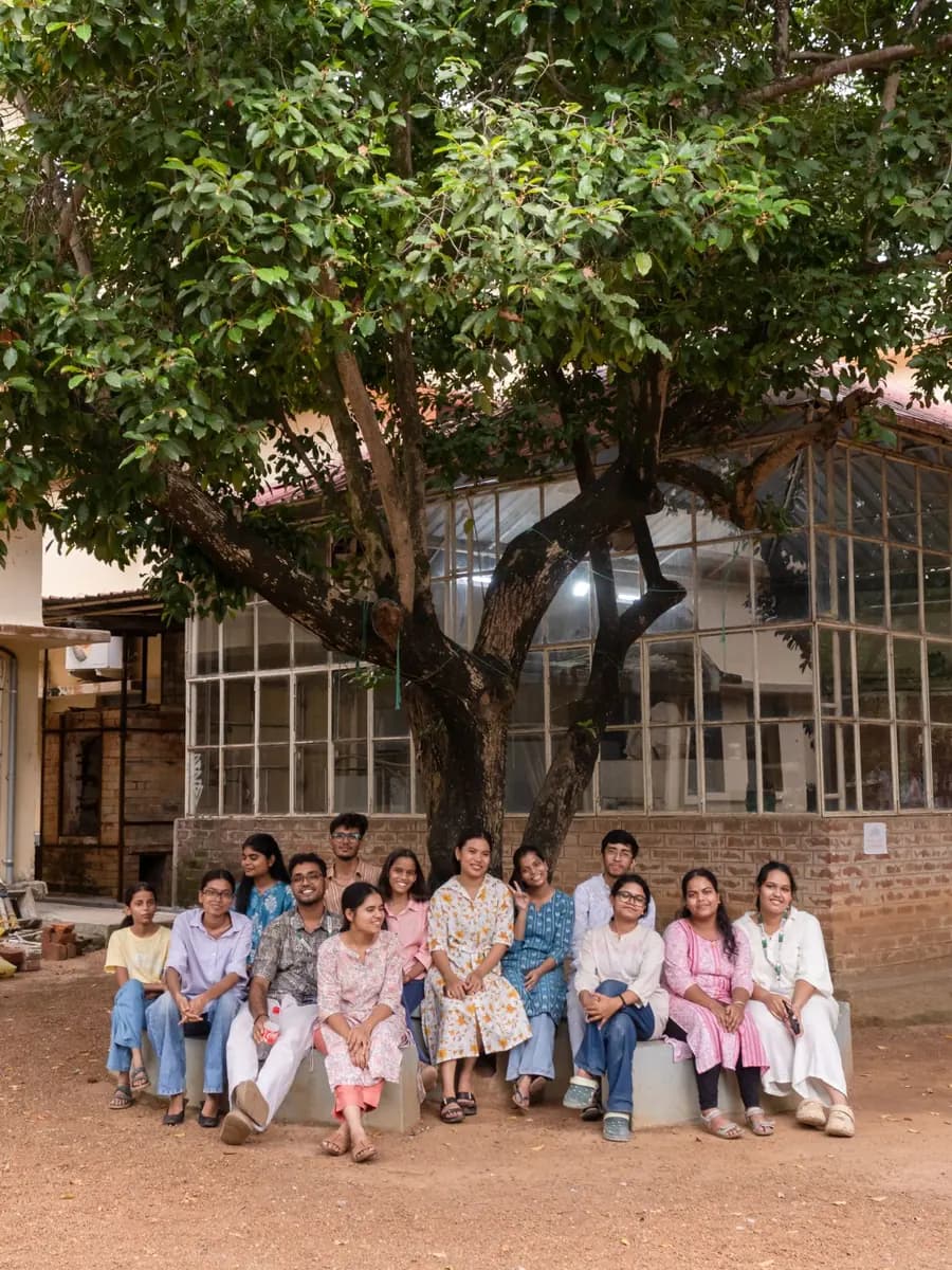 A group of college students sitting together under a big tree on campus