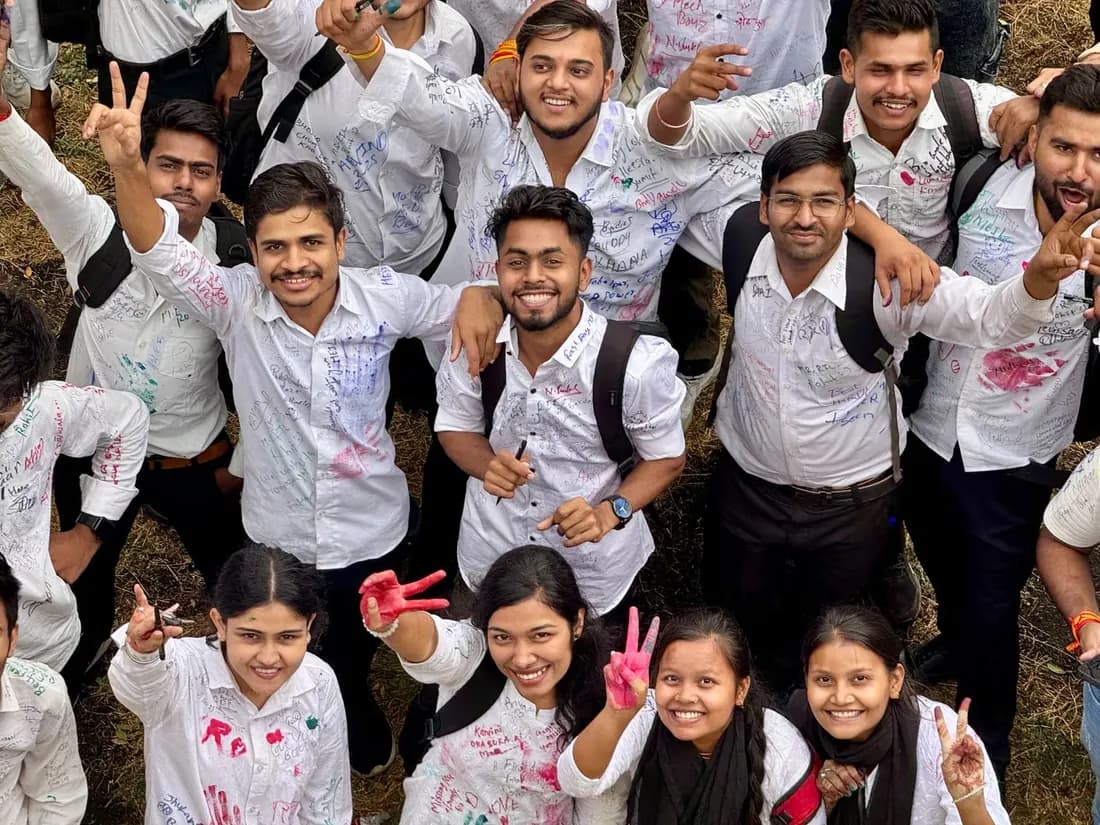 A big group of college students in signed white shirts celebrating their farewell day