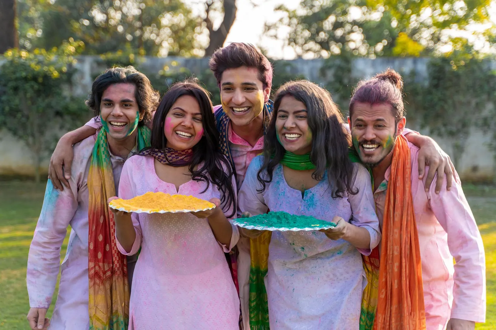 Friends laughing together on Holi, faces dusted with colour