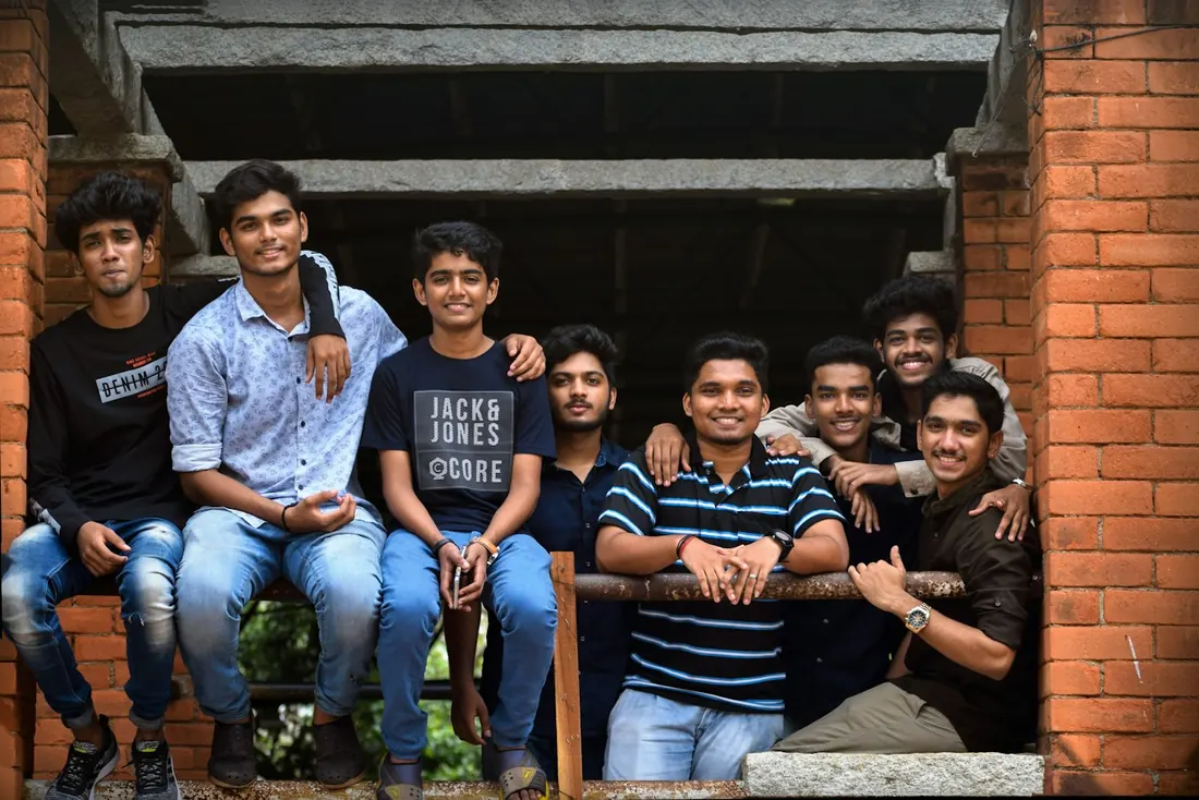 A group of college friends sitting together on steps outside a brick building