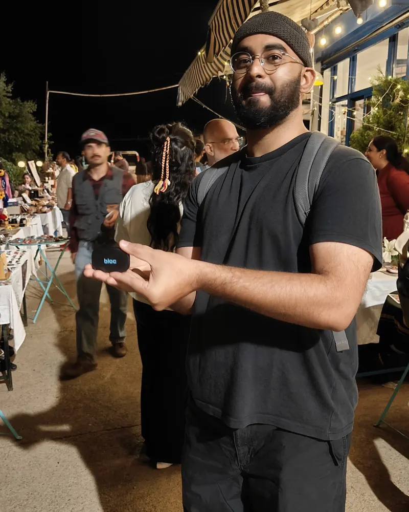 A member at a night market extending his open palm with his bloc resting on it