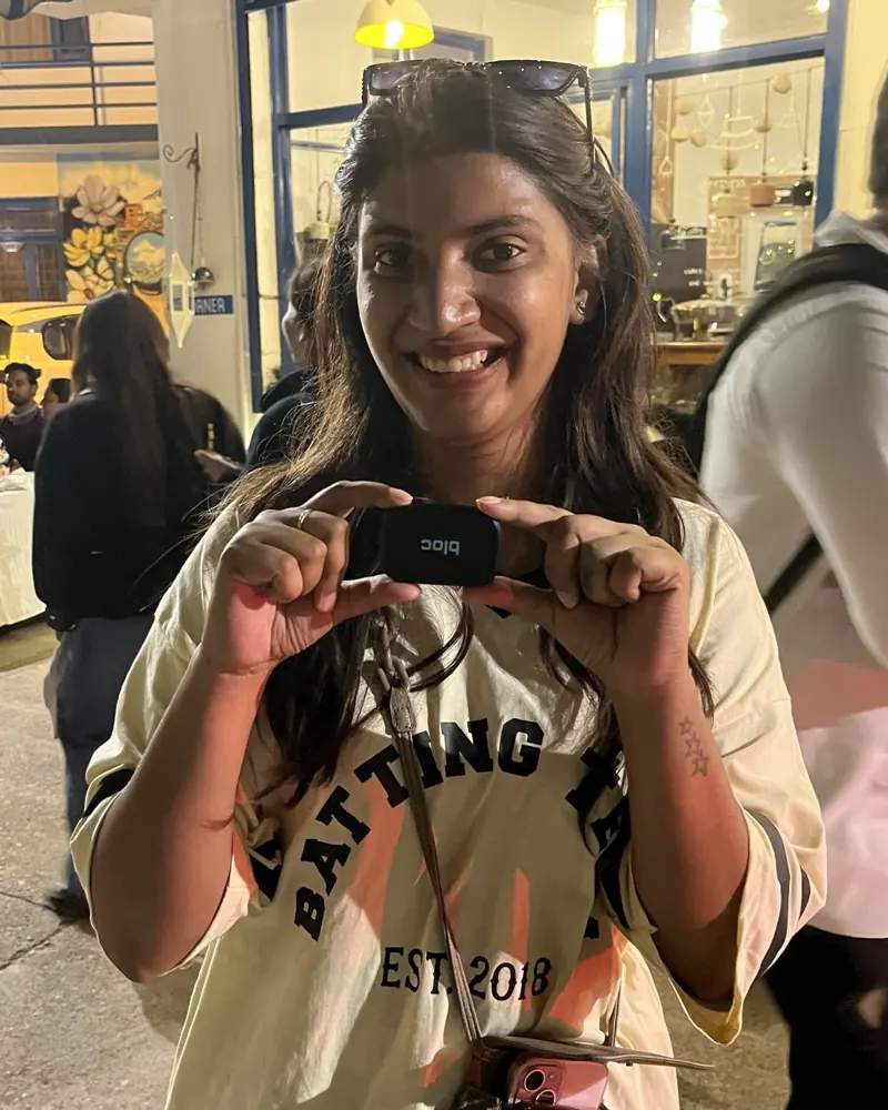 A member outside a warmly lit storefront at night, holding her bloc up with both hands