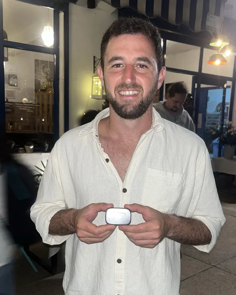 A member outside a blue and white cafe at night, holding a white bloc with both hands