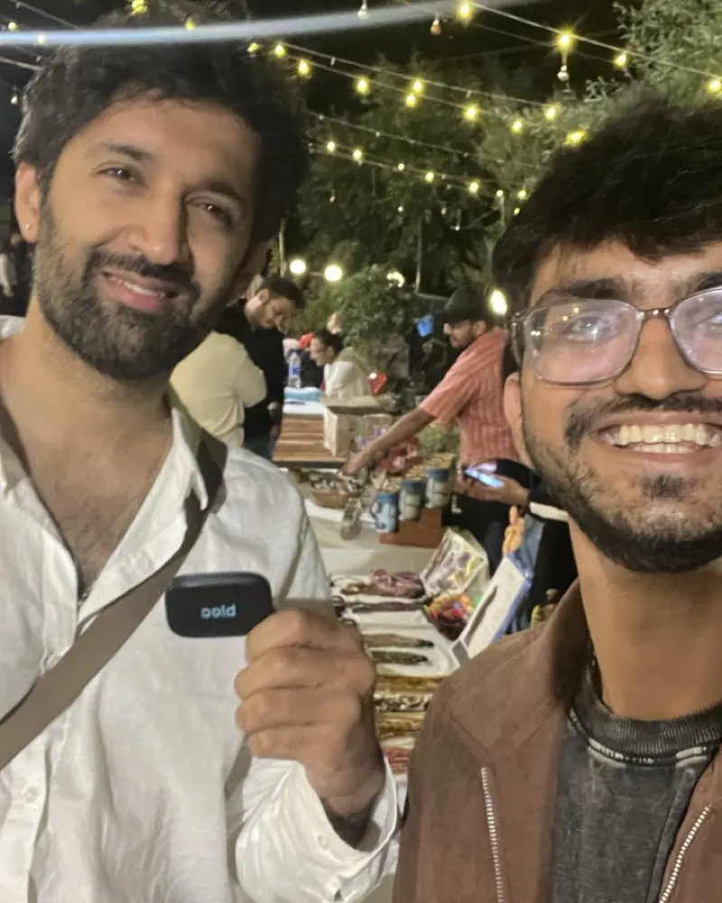 Two members at a night market lit by fairy lights, one holding his bloc at chest height