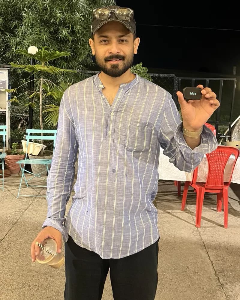 A member in a cap at a garden cafe at night, holding his bloc up in one hand