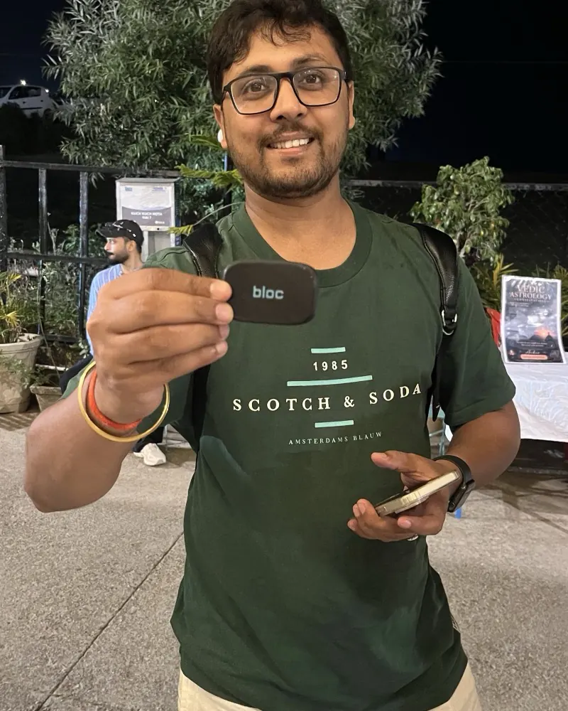 A smiling member in glasses at night, holding his bloc toward the camera