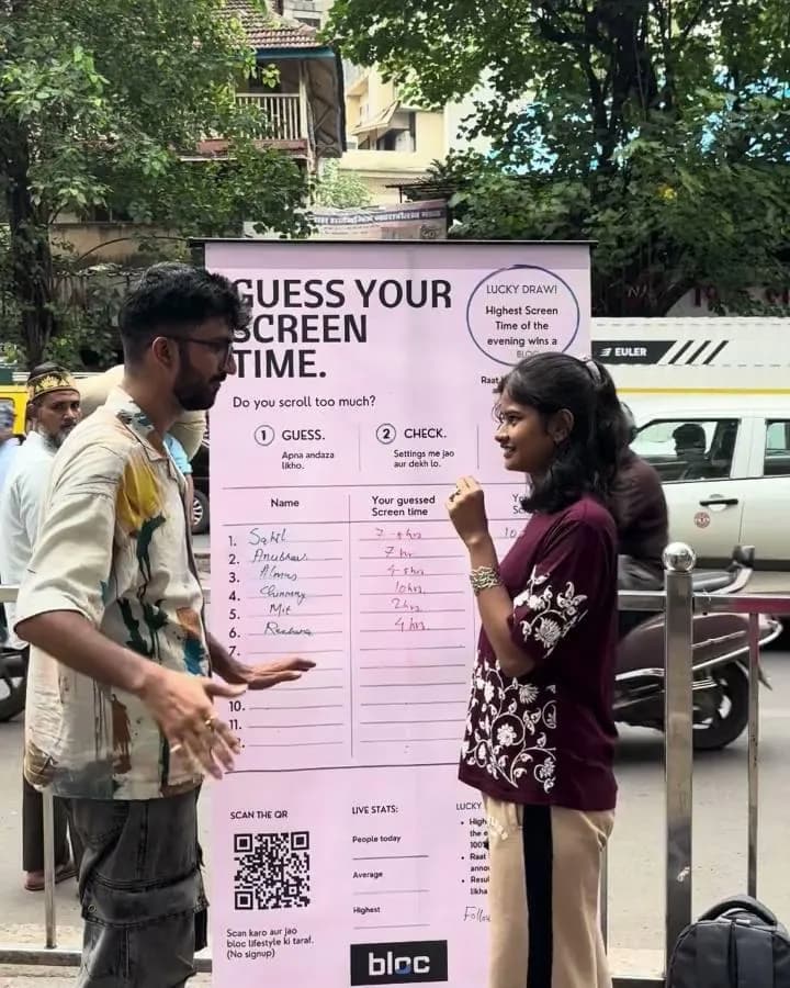 A young woman at the Guess your screen time board by a Dadar roadside, names and numbers written on it
