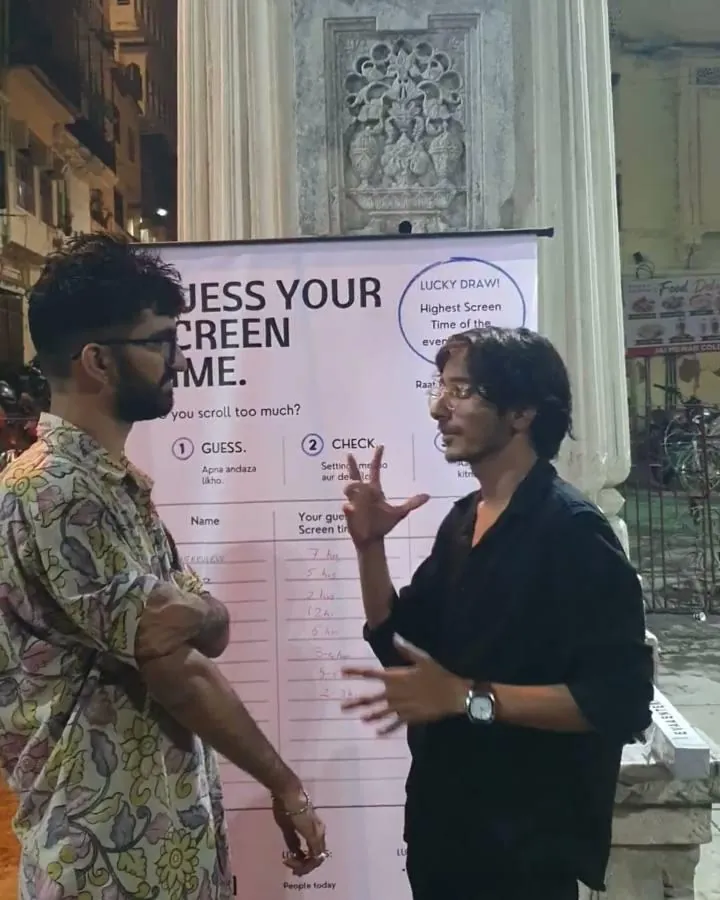A young man in a black shirt explaining something with his hands at the board at Gangaur Ghat