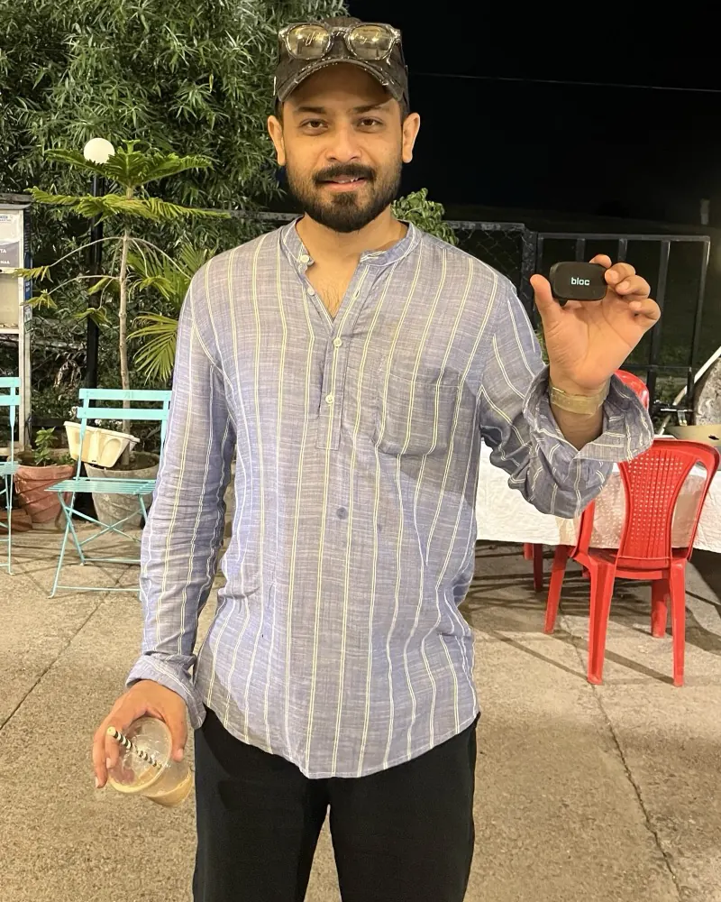 A bloc owner in a cap at a garden cafe at night, holding his bloc up in one hand