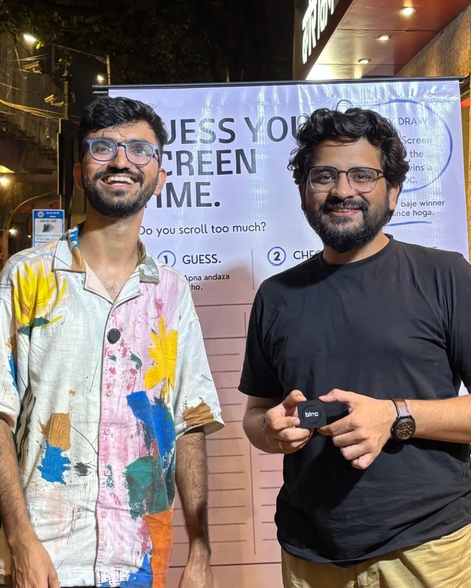Two men smiling at the board in Lower Parel at night, one holding a bloc